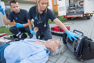 EMTs caring for man lying on sidewalk